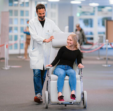 Ein Begleiter bringt eine Patientin zu einer Untersuchung Ein Begleiter bringt eine Patientin zu einer Untersuchung